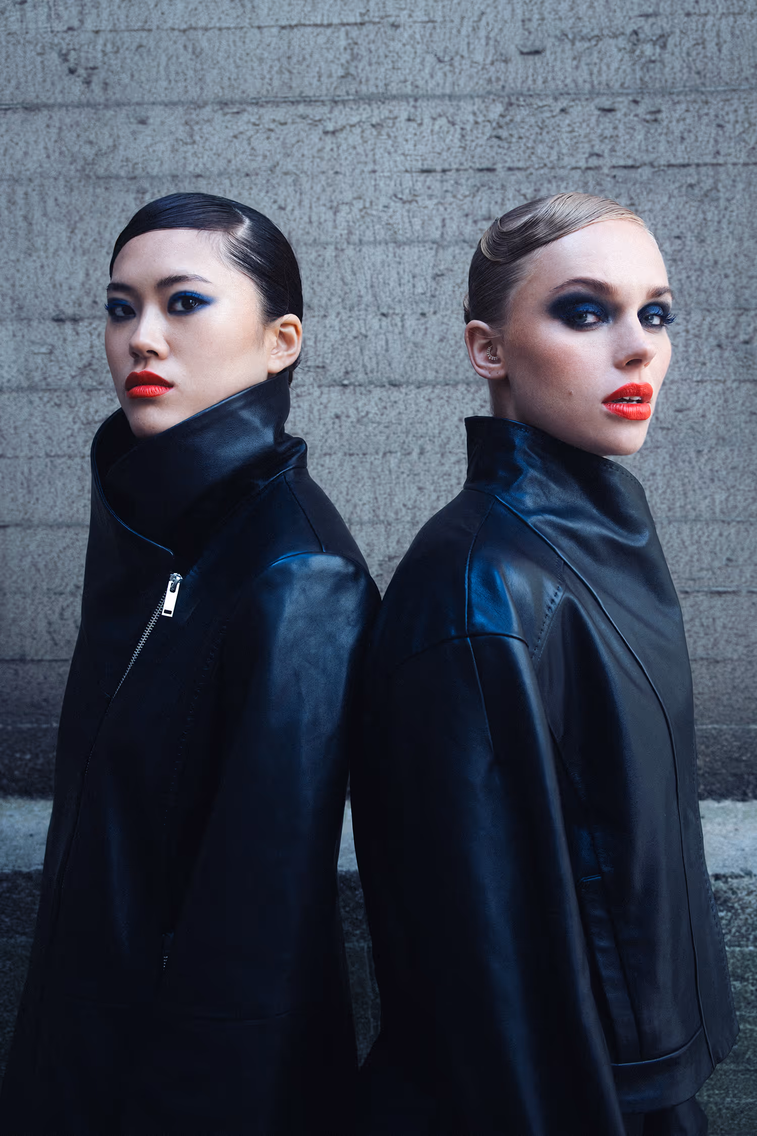 Two women dressed in black back to back facing away from each other