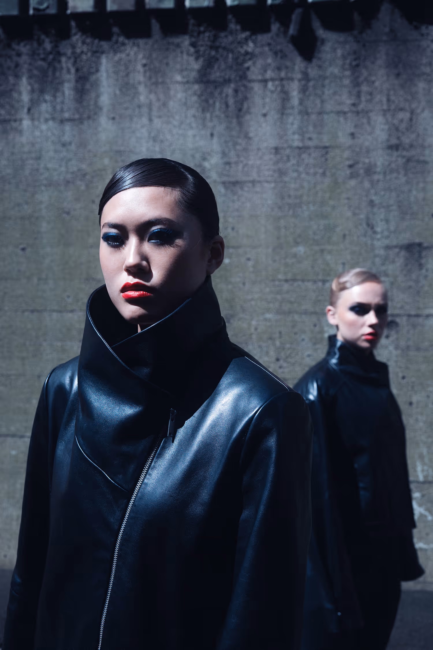 Two women dressed in black standing by the wall