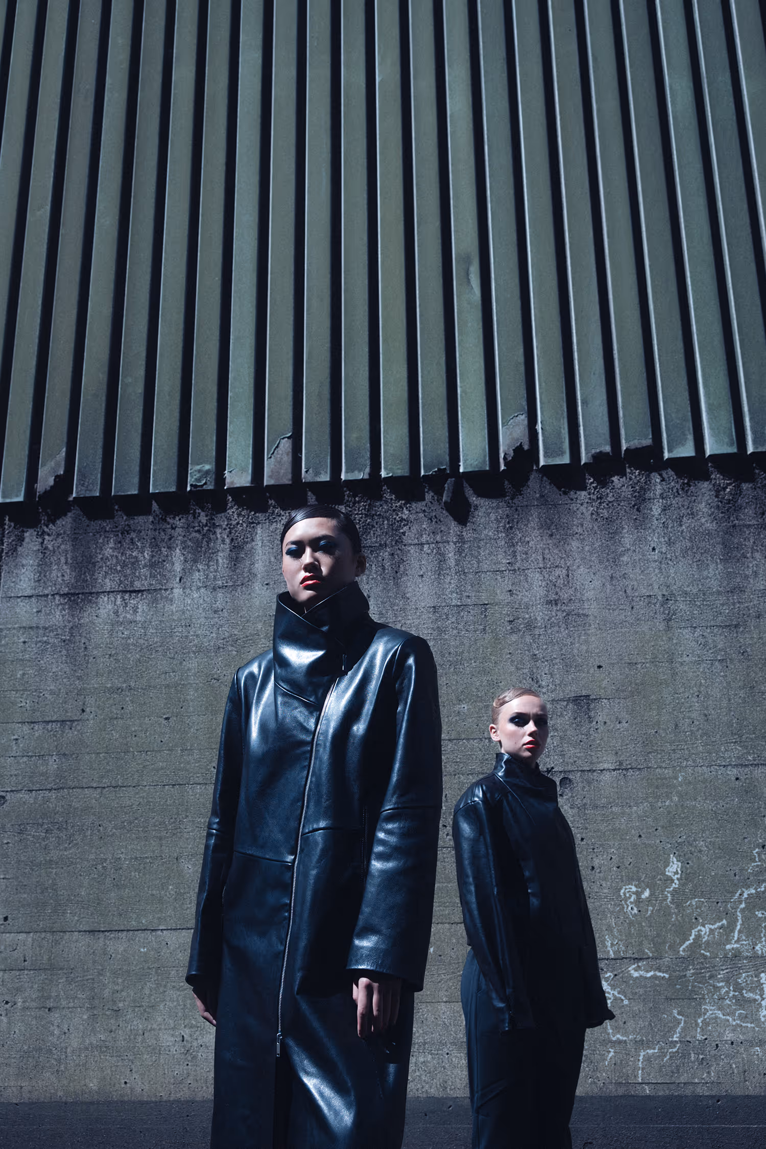 Two women dressed in black standing by the wall