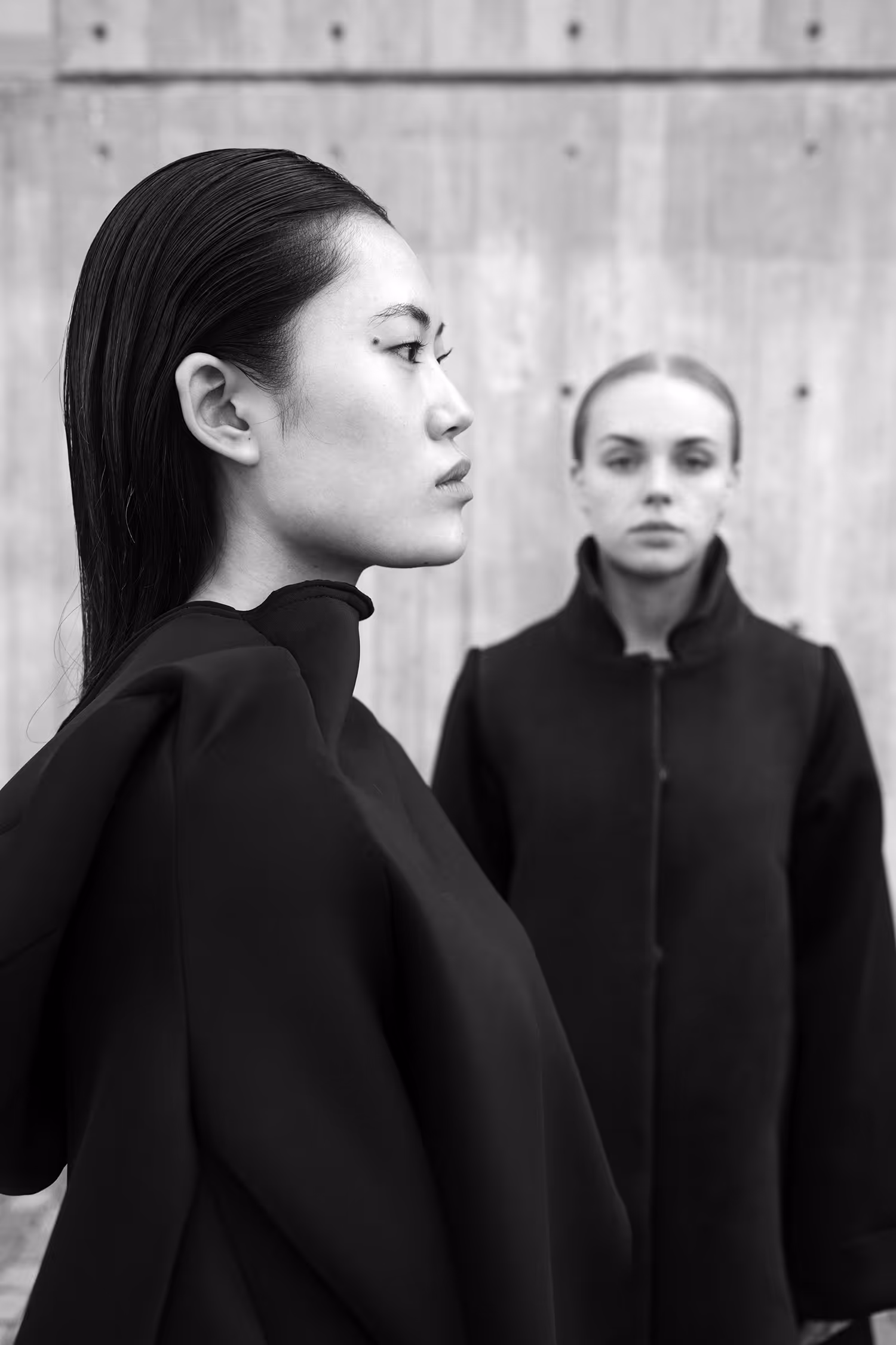 Two women in a minimalist space; one clear in the background