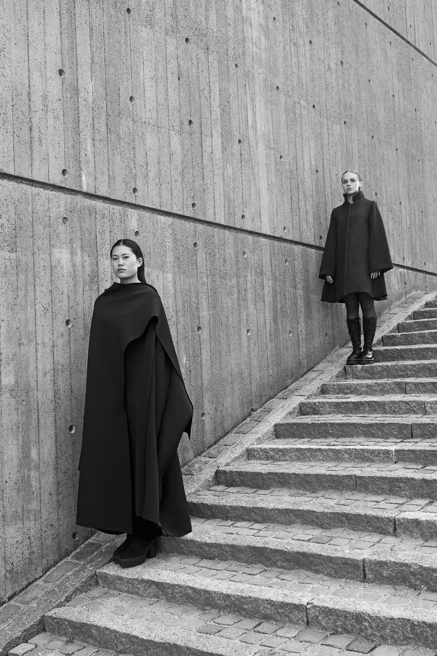Two women standing on the stairs by the wall