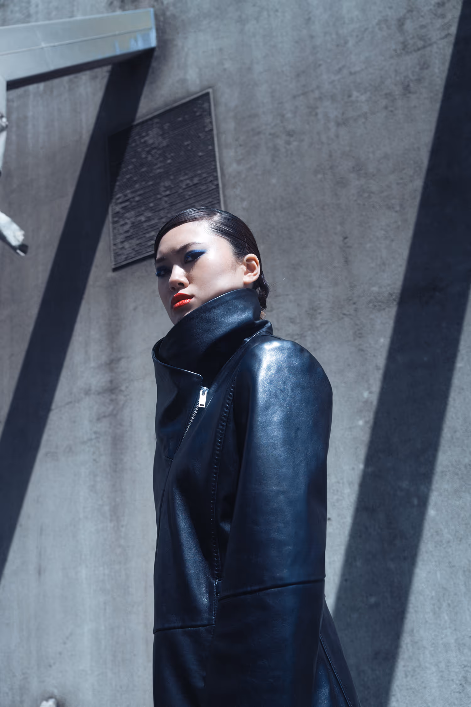 Woman in a leather coat standing by the wall