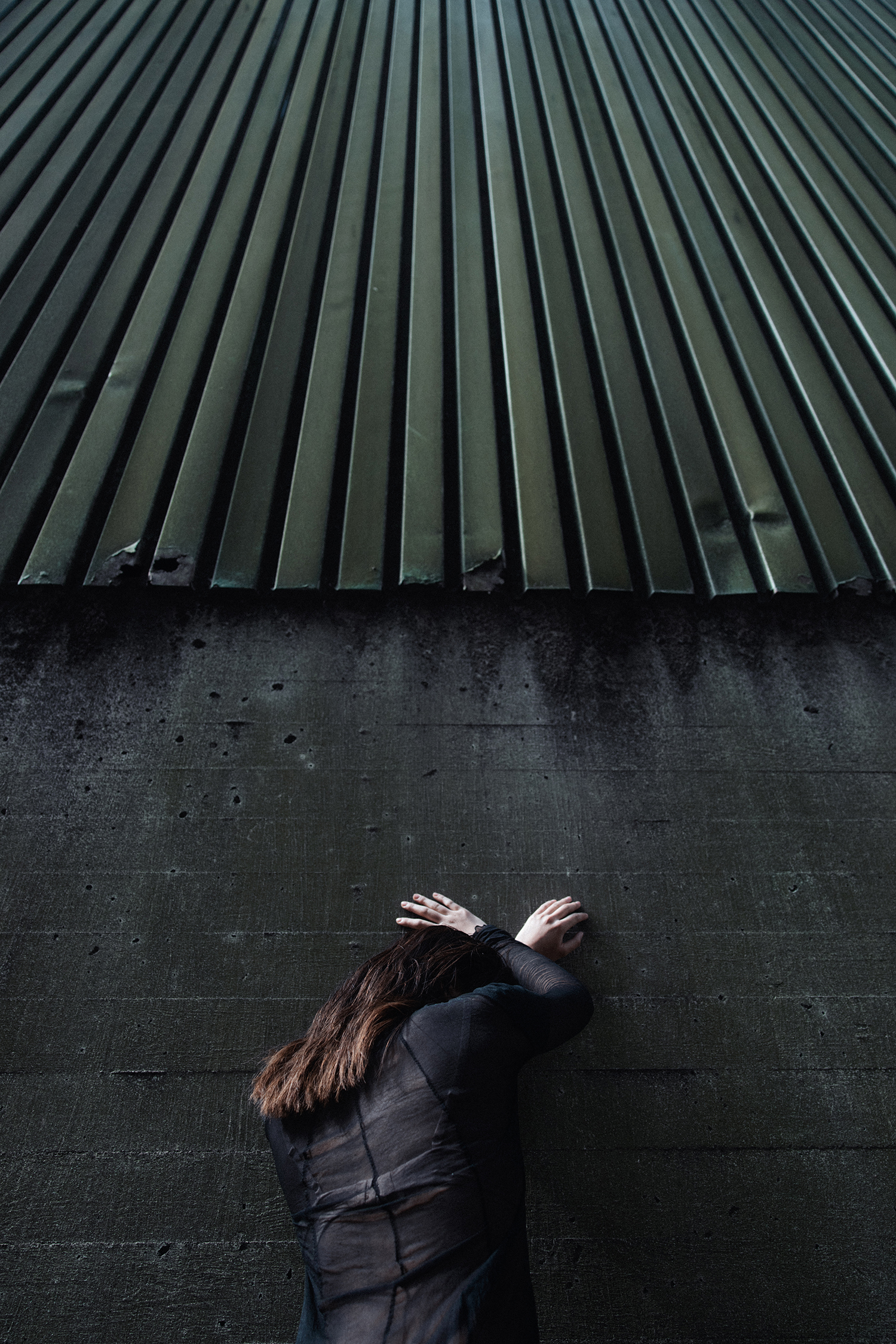 Woman standing facing the wall leaning on it with her hands
