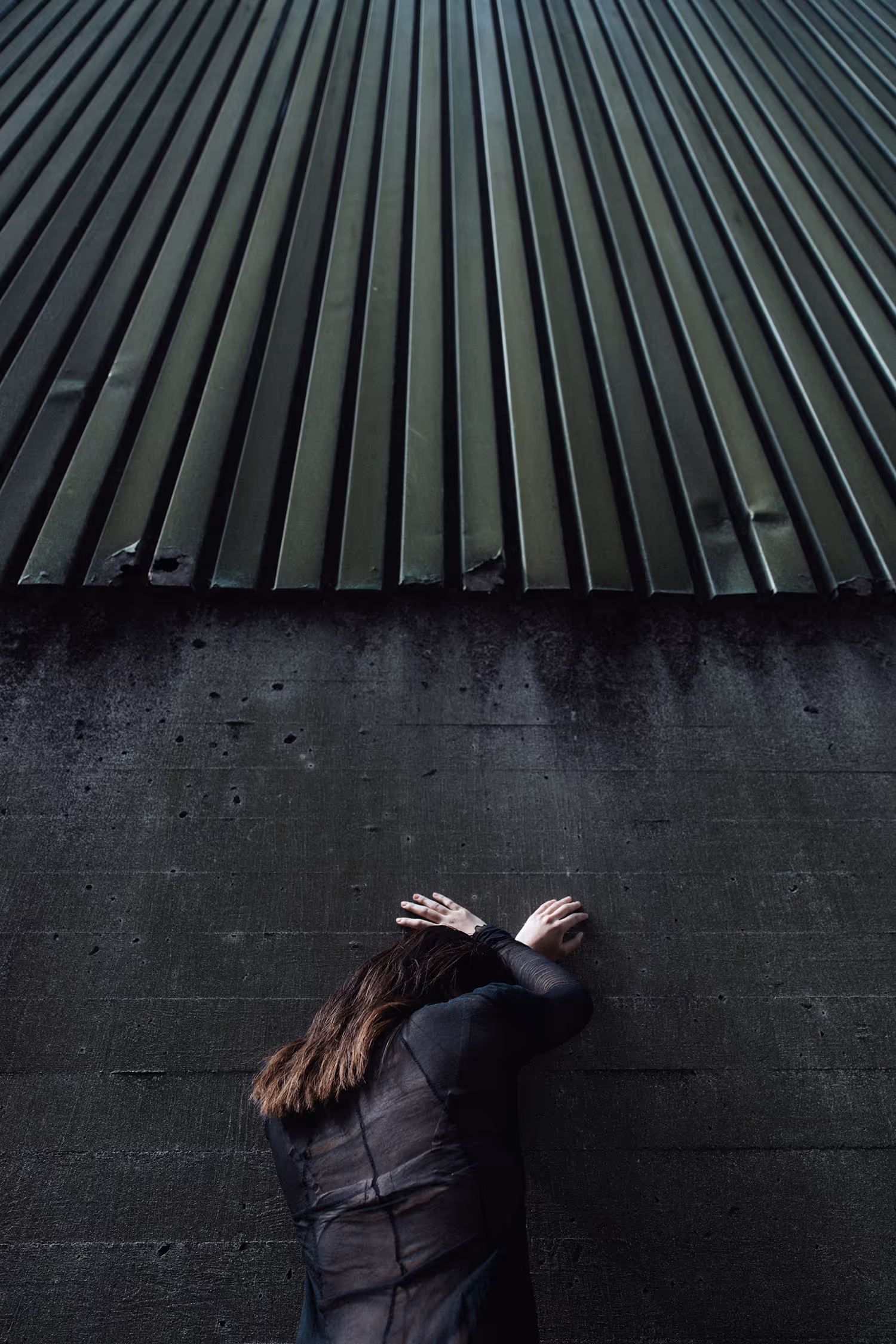 Woman standing facing the wall leaning on it with her hands